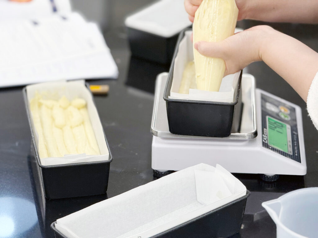 제과기능사-틀에 넣은 반죽을 저울에 올려 계량하는 사진