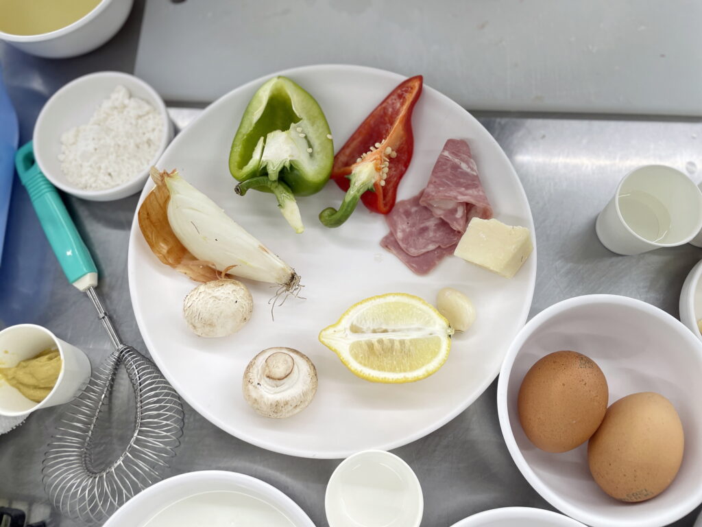 접시에 깔끔하게 분리되어 전처리를 기다리는 식재료들 - 피망, 양파, 레몬, 베이컨 등